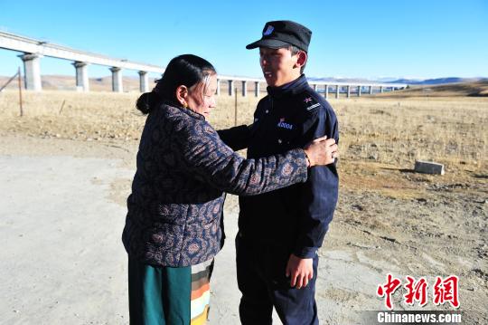 图为10月30日，欧玛停格护路联防大队副大队长扎西旺久的母亲到大队探望时为小队员贡桑整理衣服。　张伟 摄